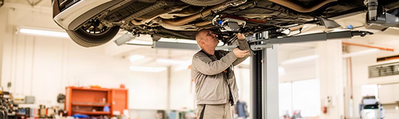 Mechanic inspecting a vehicle on a lift inside a clean Vaughan automotive workshop