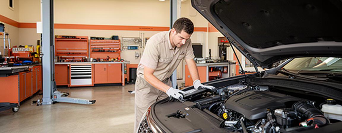Certified mechanic inspecting an engine inside a clean modern auto repair shop